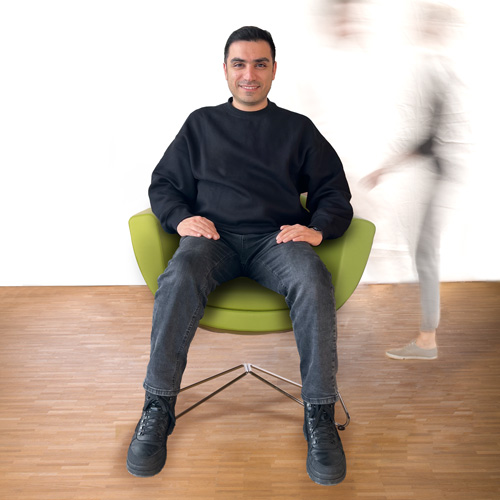 Mitarbeiter Arash sitzt auf dem grünen Stuhl