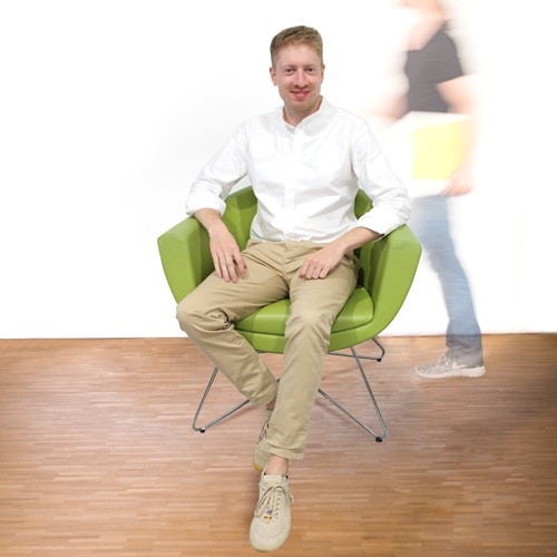 Mitarbeiter Erik sitzt auf dem grünen Stuhl
