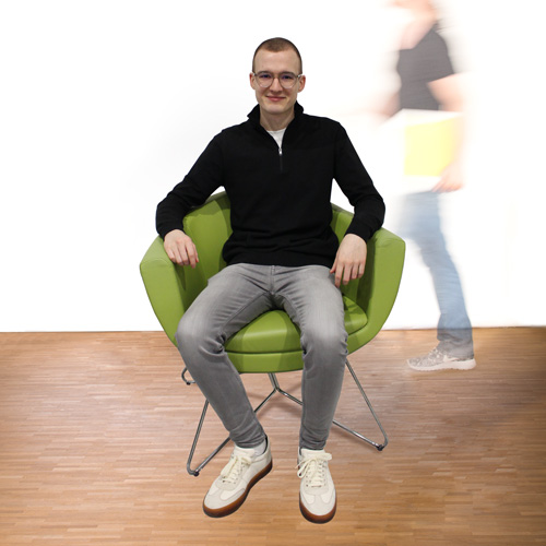 Mitarbeiter Andreas sitzt auf dem grünen Stuhl