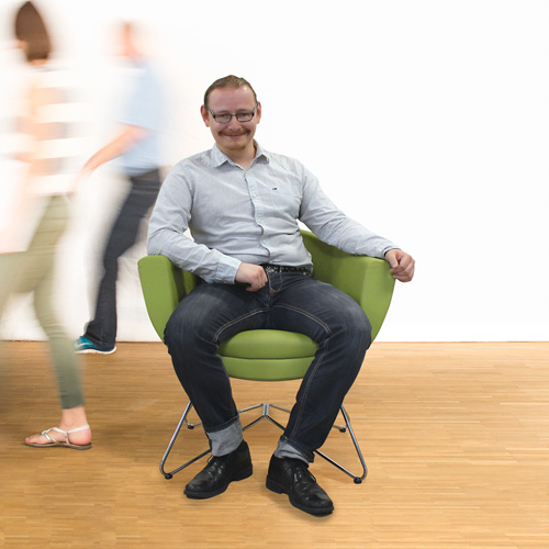 Mitarbeiter Florian sitzt auf dem grünen Stuhl