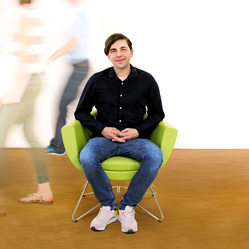 Mitarbeiter Gregor sitzt auf dem grünen Stuhl